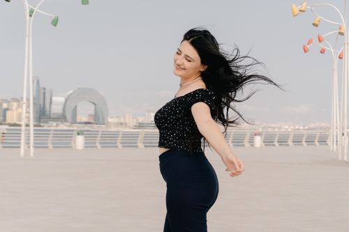 Free Happy woman enjoying a sunny day at Baku Seaside Boulevard with iconic cityscape view. Stock Photo