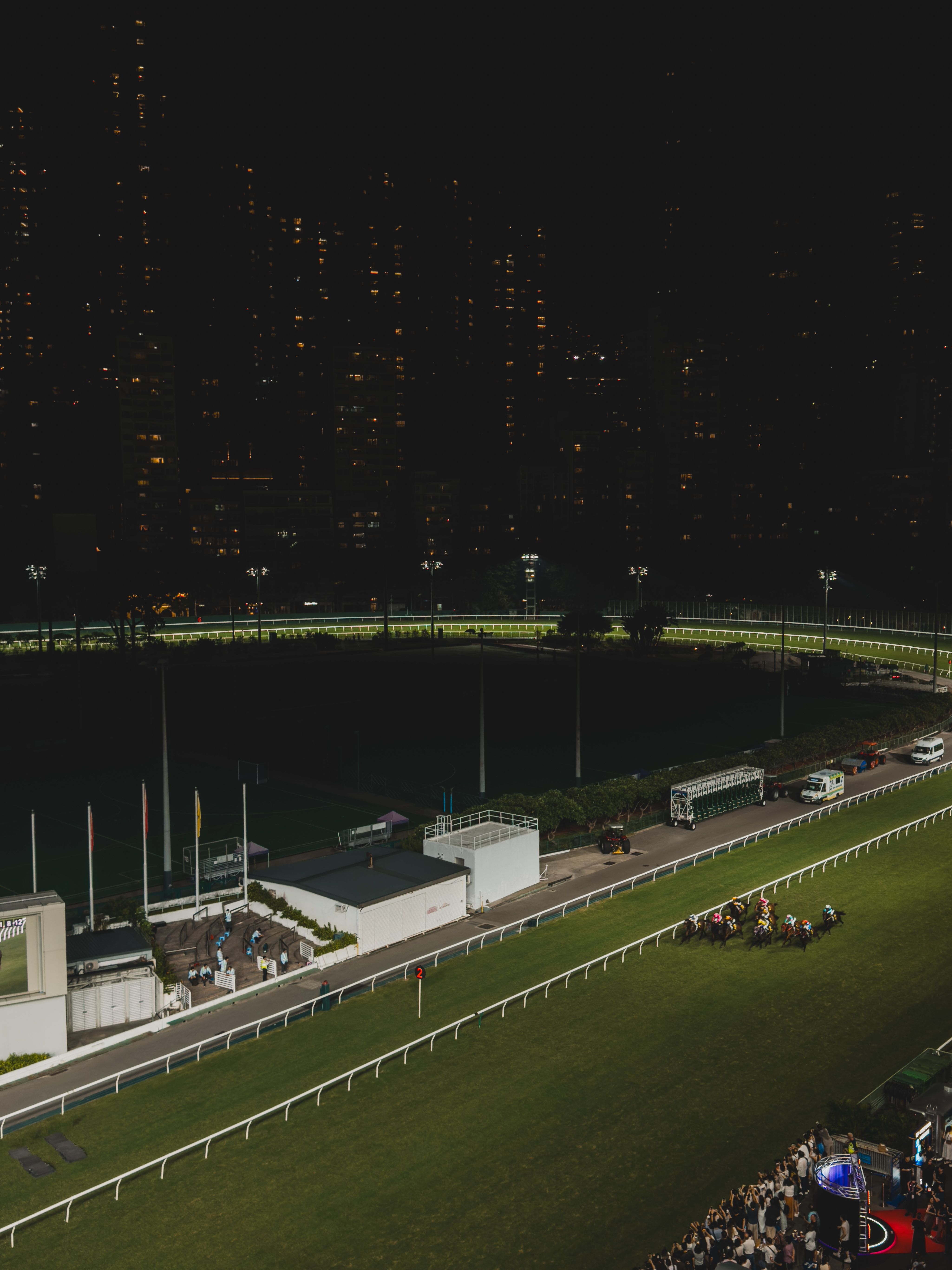 Horse racing event under city lights at night in Hong Kong Island, showcasing vibrant urban backdrop.