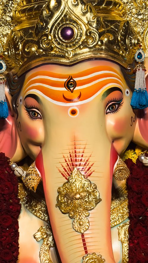 Free Vibrant close-up of Ganesha idol adorned with gold crown and intricate details. Perfect for cultural and religious themes. Stock Photo
