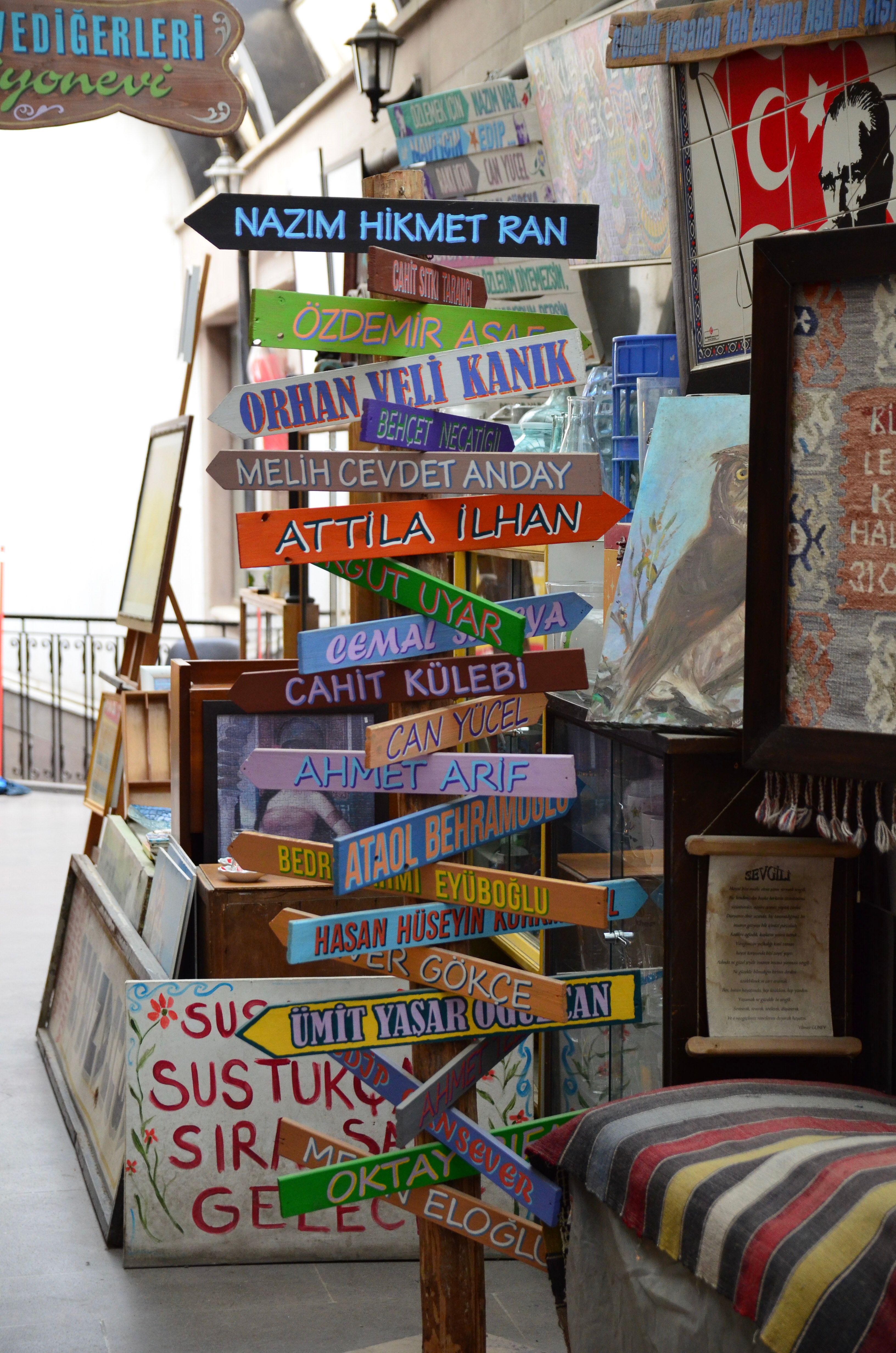 Vibrant signpost featuring Turkish poets' names inside a retro-themed store.