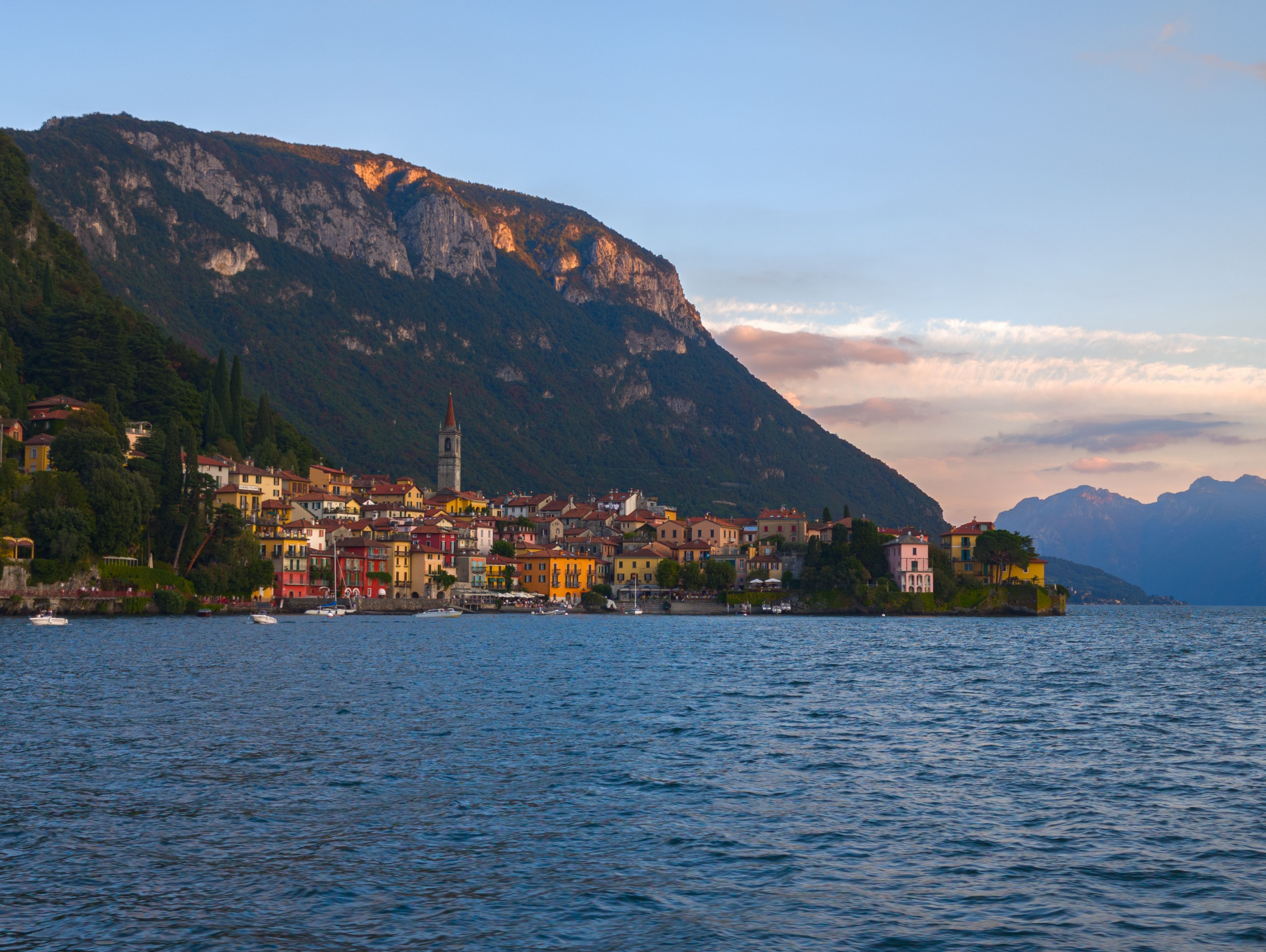 Colorful houses of Varenna by Lake Como with mountain backdrop at sunset.
