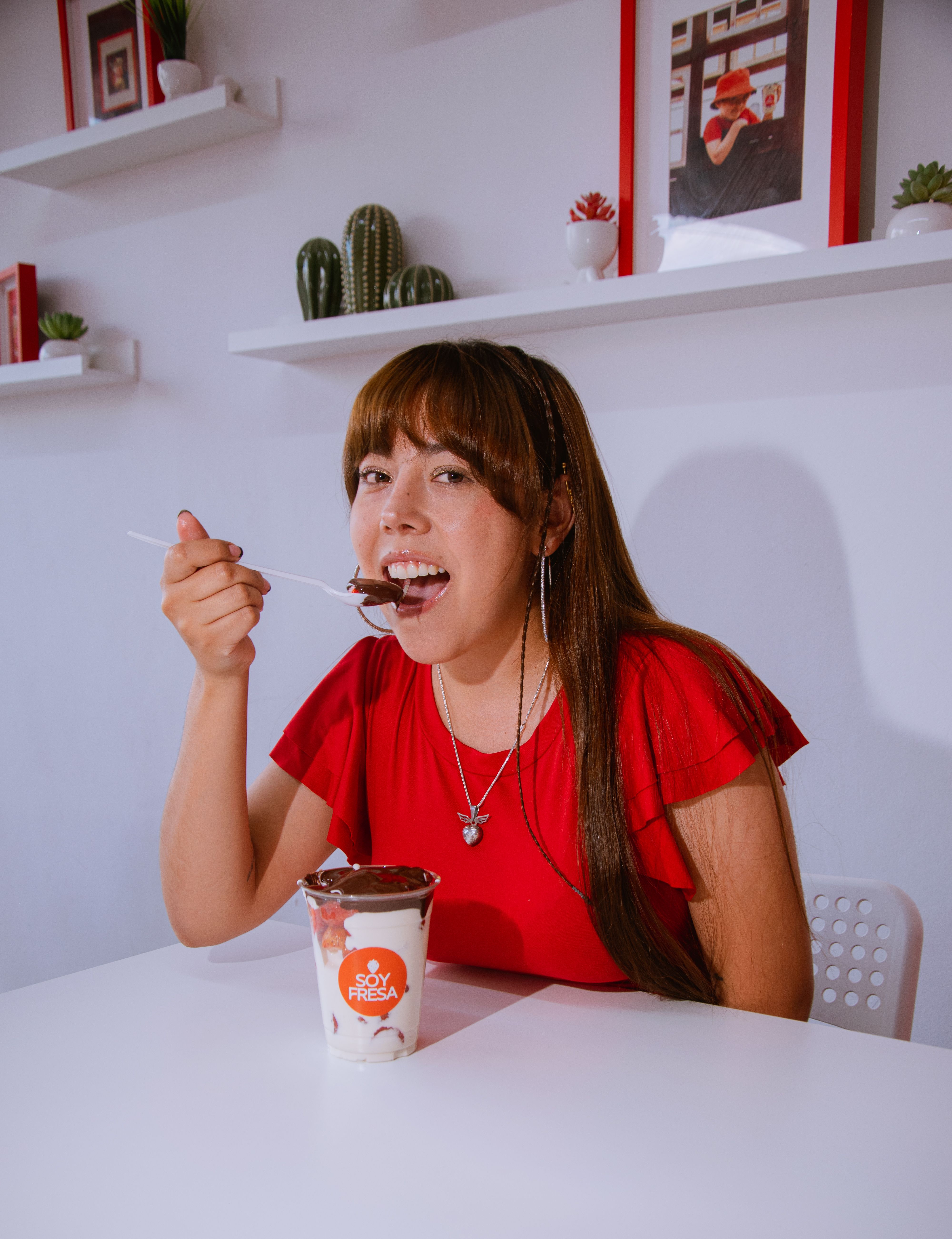 Young woman enjoys a cup of Soy Fresa yogurt in a stylish and modern kitchen space.
