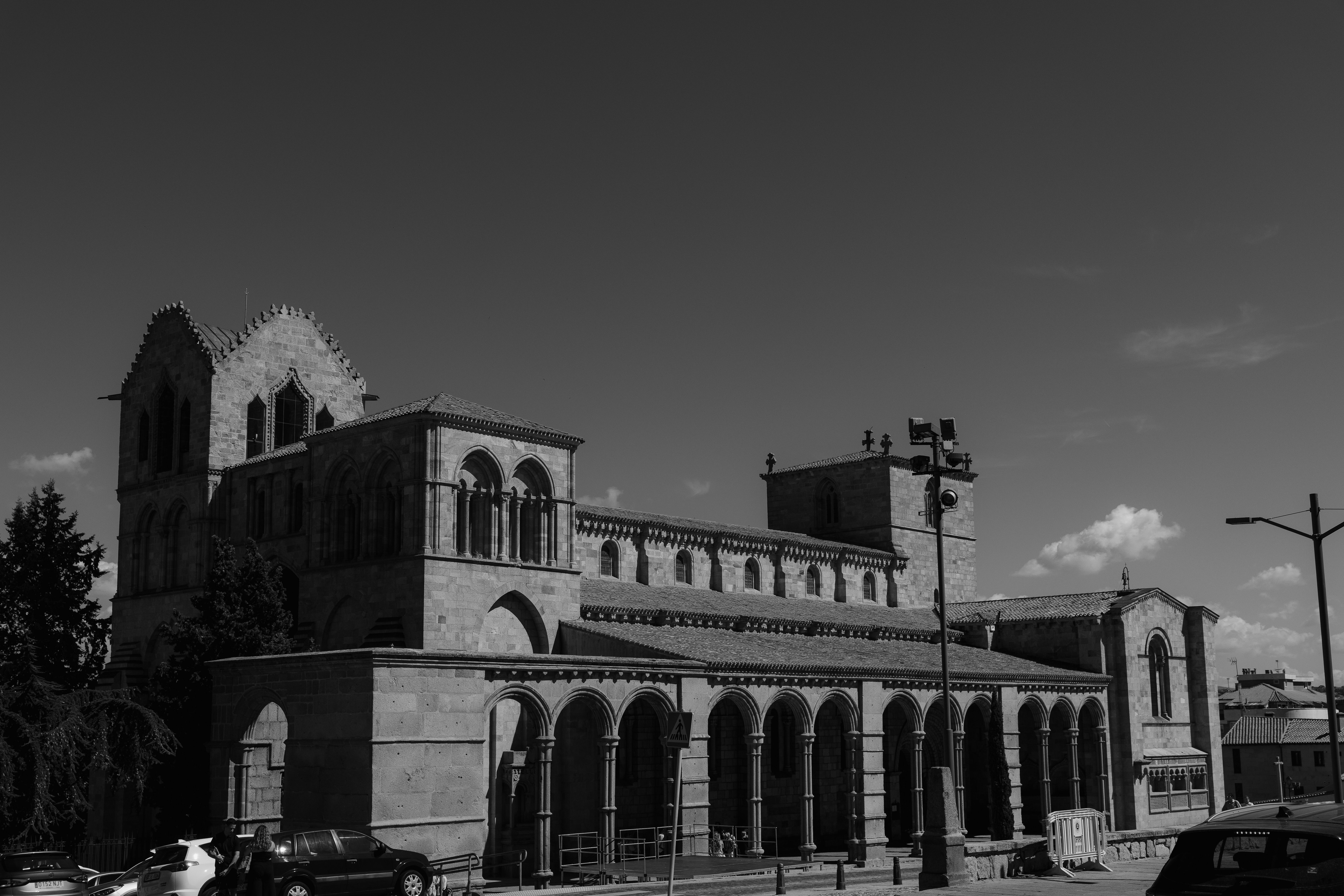 A striking black and white photo of Basilica de San Vicente, Avila, showcasing Romanesque architecture under a clear sky.