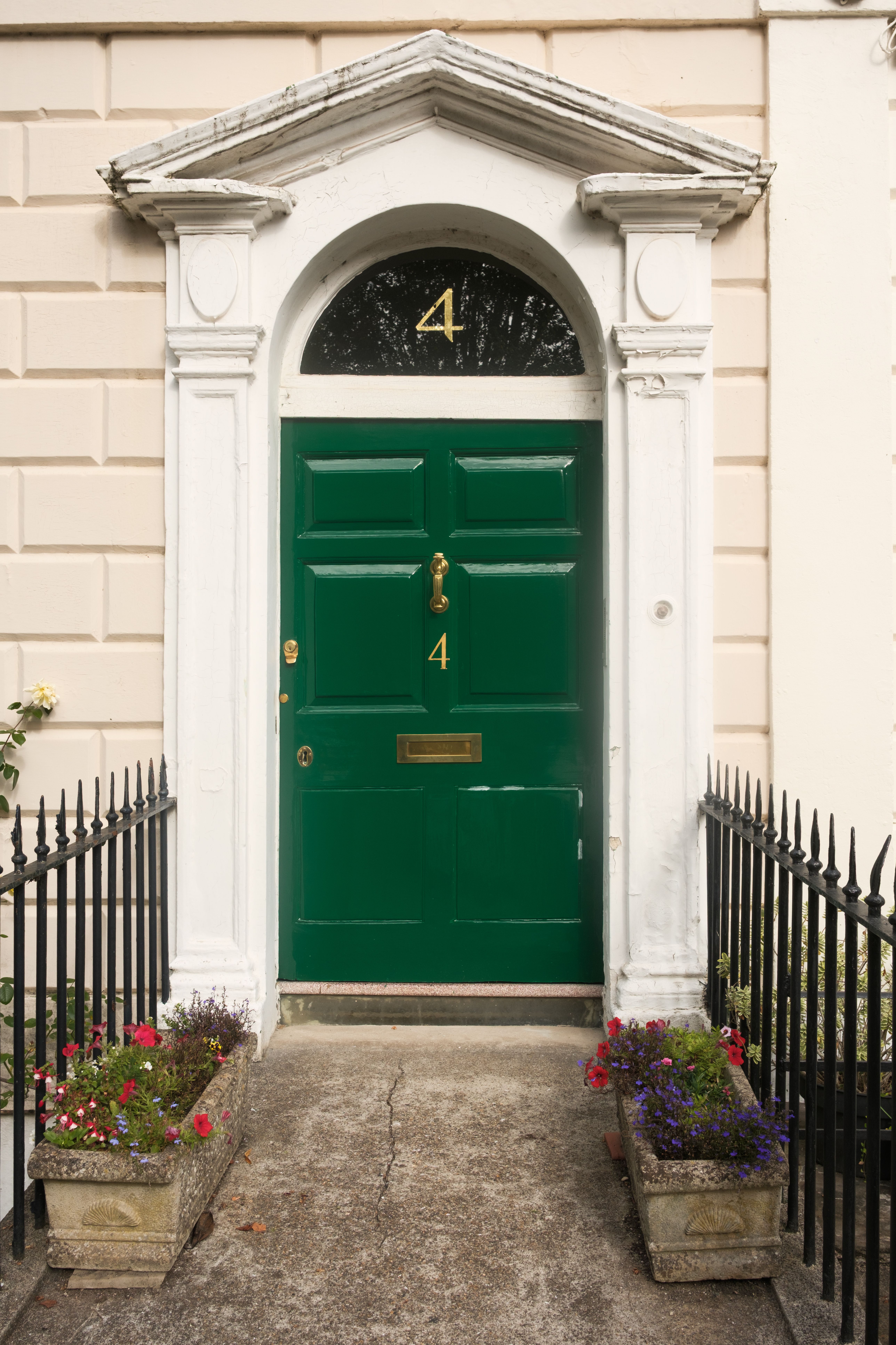 Elegant green door with number 4 in a Georgian townhouse in Bristol, flanked by flower pots.