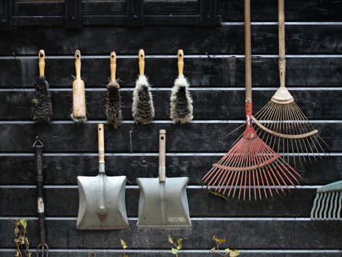 Garden tools neatly arranged on a rustic wooden wall