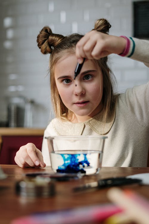 Girl Dropping Blue Dye on Bowl with Water