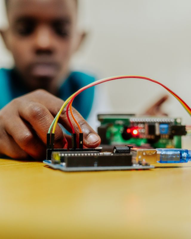 A young student prototyping an electronic circuit with an Arduino and breadboard