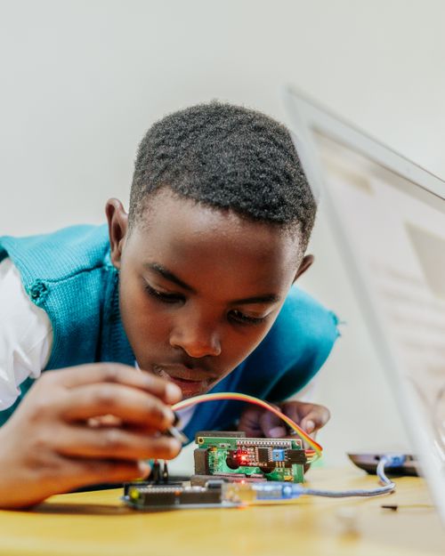 Free Young boy engaged in building an electronics circuit on a desk. Stock Photo