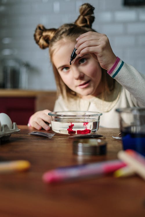 Girl Slowly Dropping Blue Color on Bowl with Water