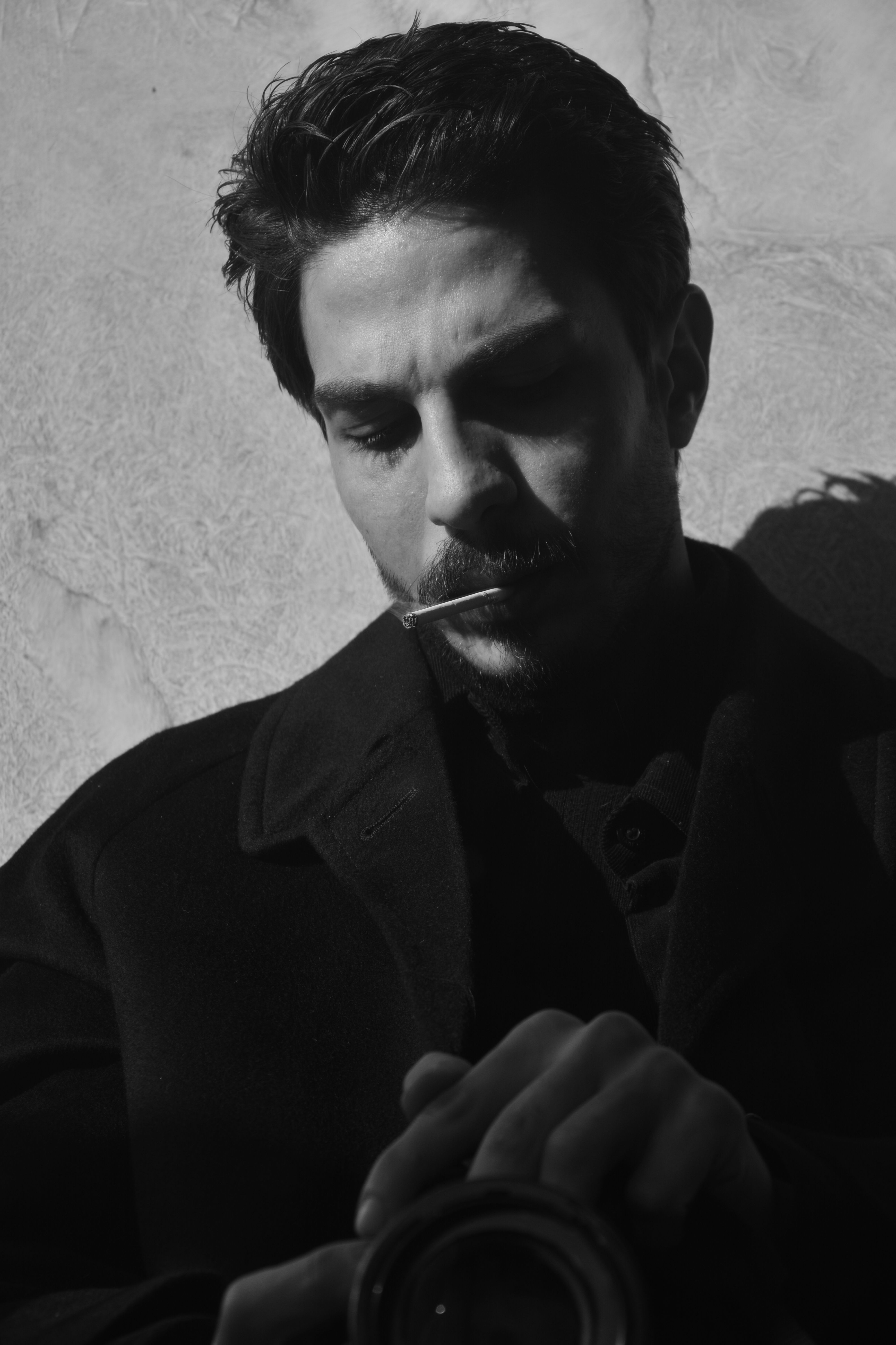 Black and white portrait of a man with dramatic shadows, conveying a moody atmosphere.