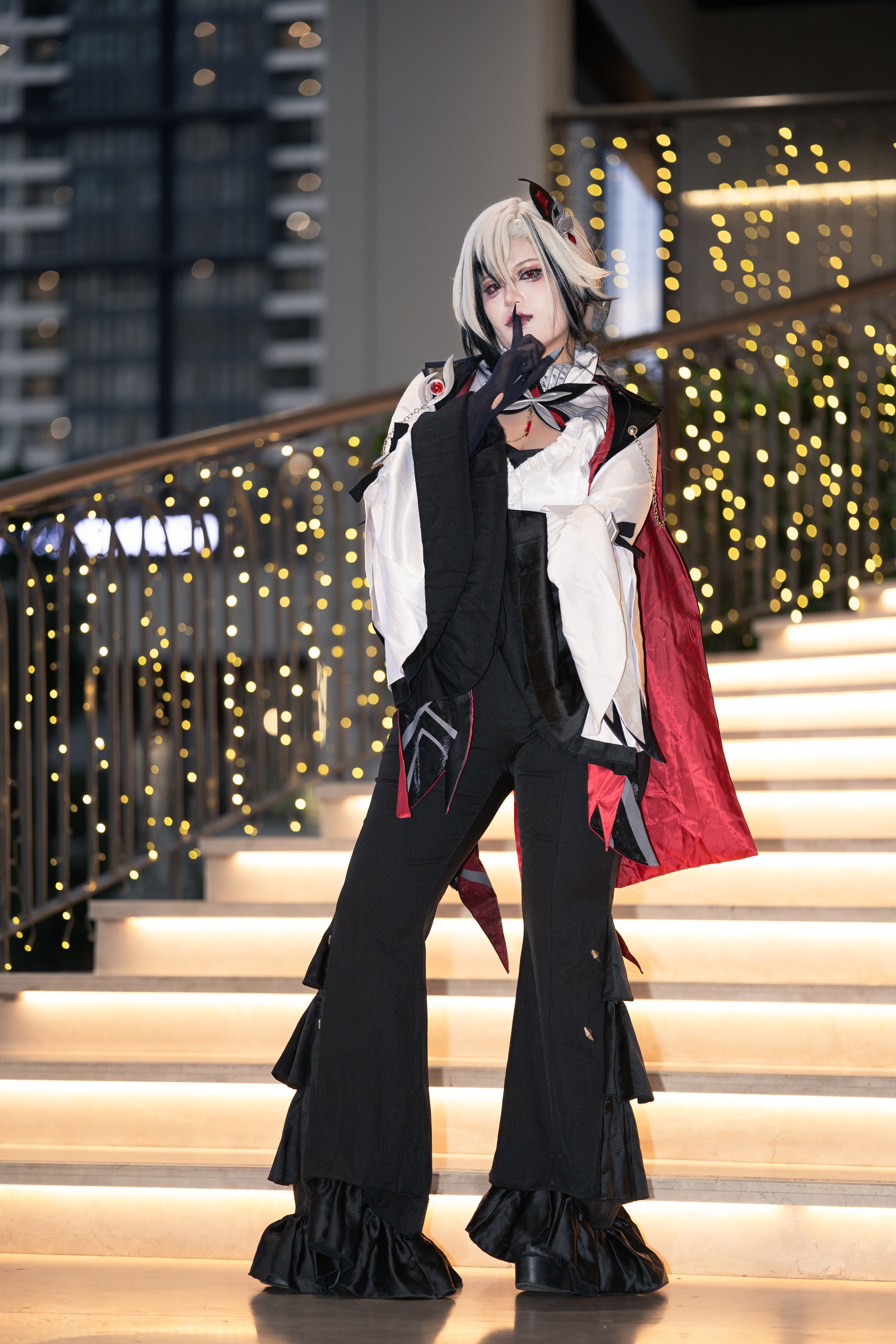 A detailed cosplay character posing on a decorated staircase indoors.