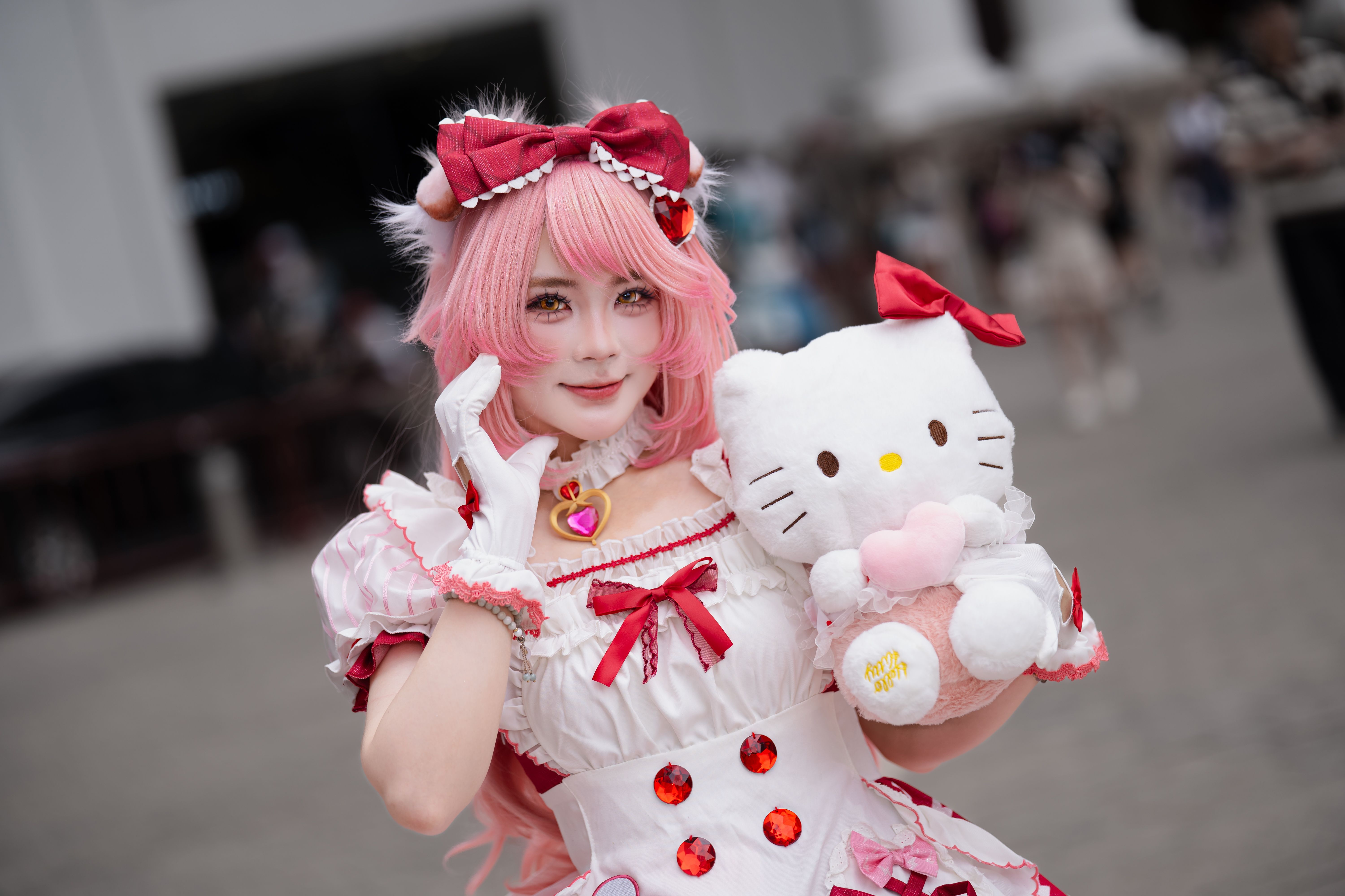 Cosplay performer in elaborate pink outfit holding a plush toy outdoors.