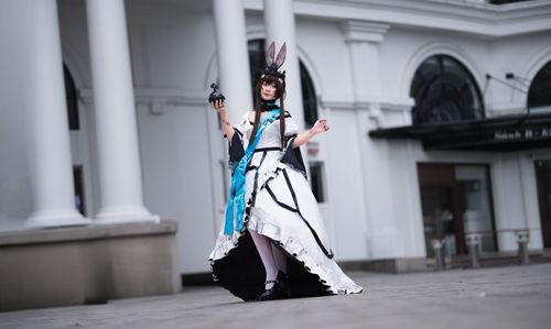 Free A cosplayer in elaborate costume poses gracefully outside a classic building. Stock Photo