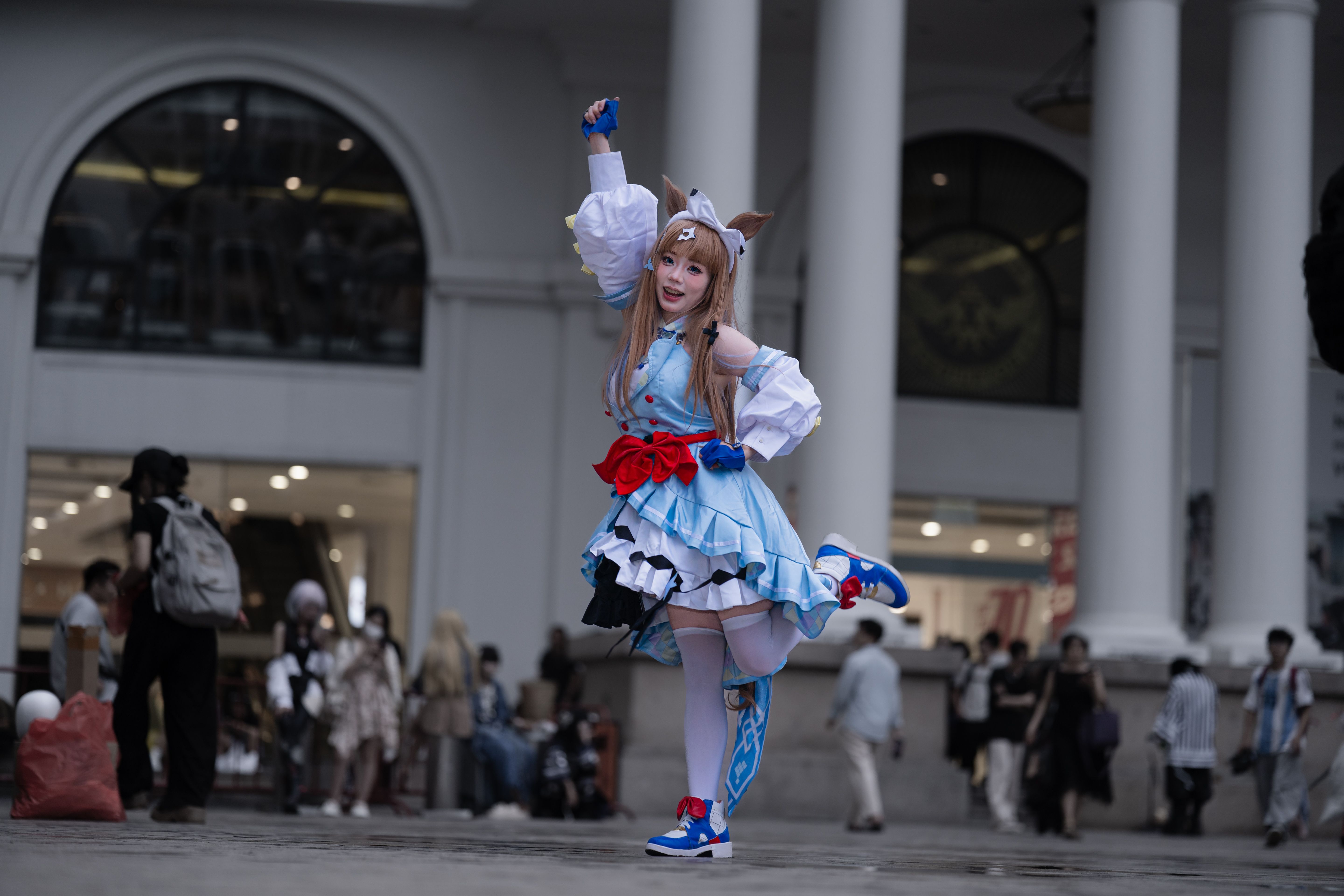 Energetic cosplayer posing in a lively outdoor setting at a convention center.