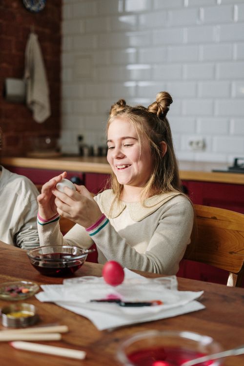 Free Child enjoying Easter egg decorating with family in cozy home kitchen. Stock Photo