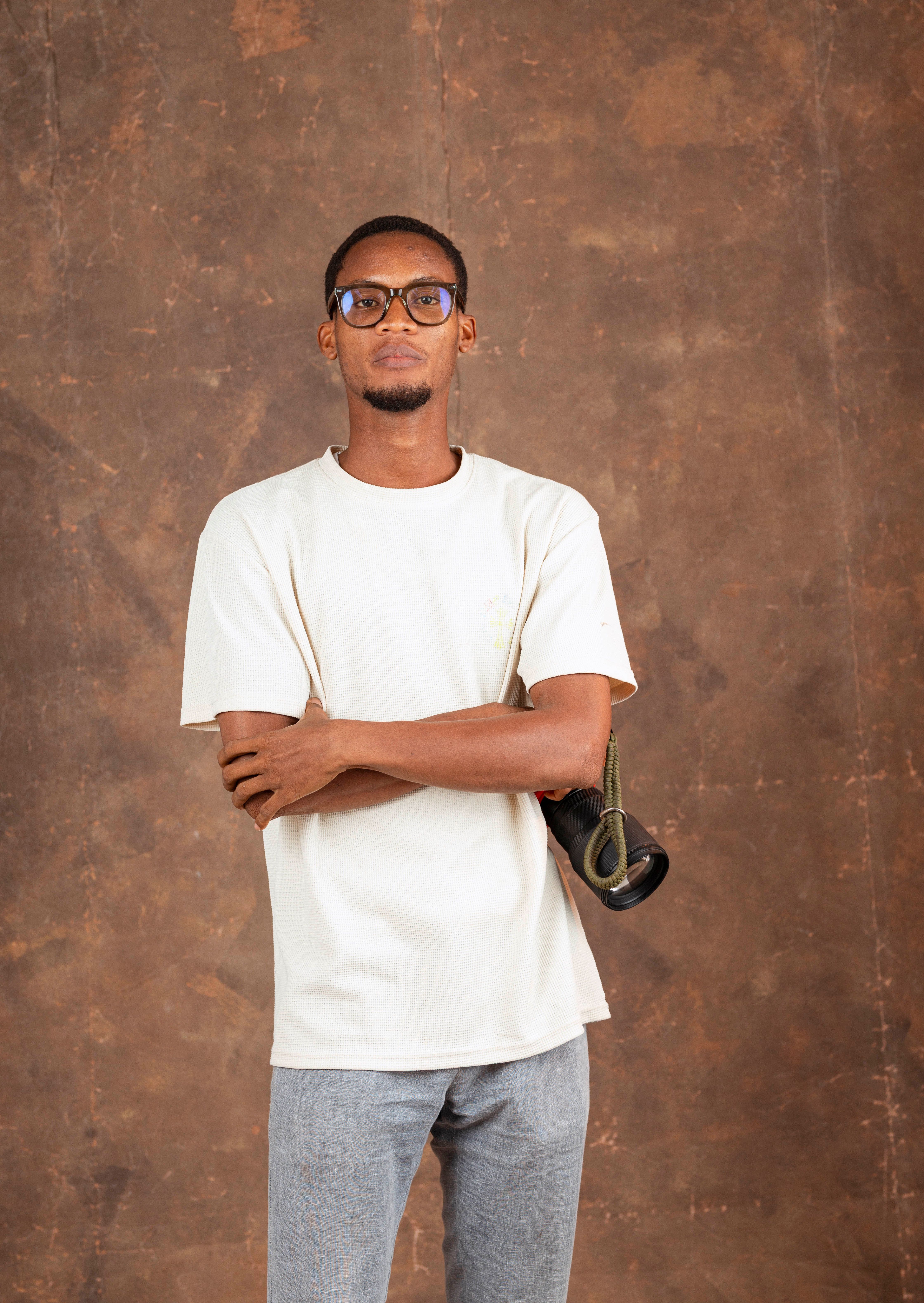 Portrait of a confident man with glasses in a studio setting holding a camera.