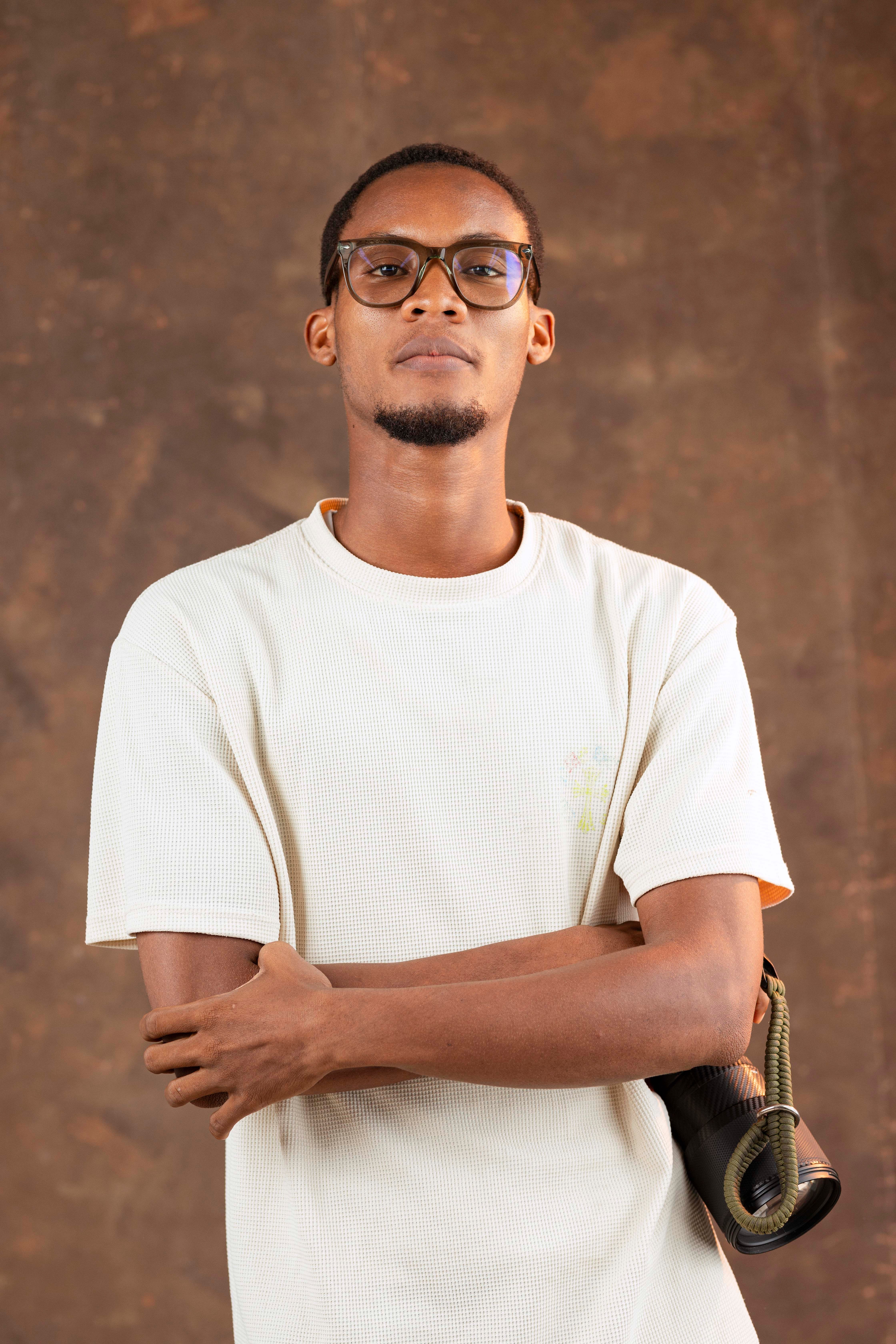 Portrait of a man in glasses with folded arms in a studio setting.