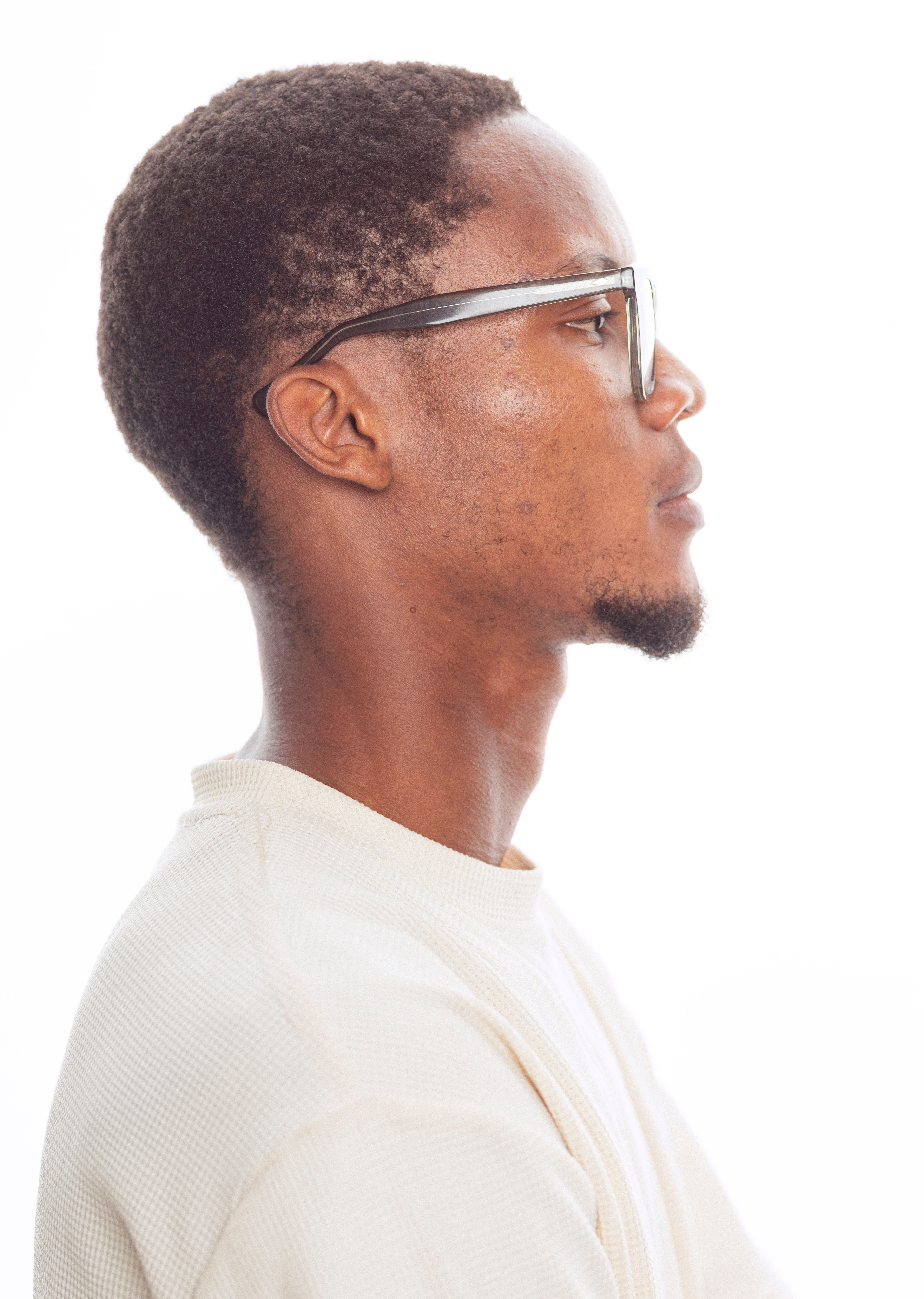 Side profile portrait of a man wearing glasses, shot in a studio setting.