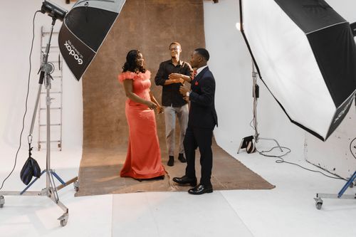 Free Three adults in a photography studio setting up a portrait shoot. Stock Photo
