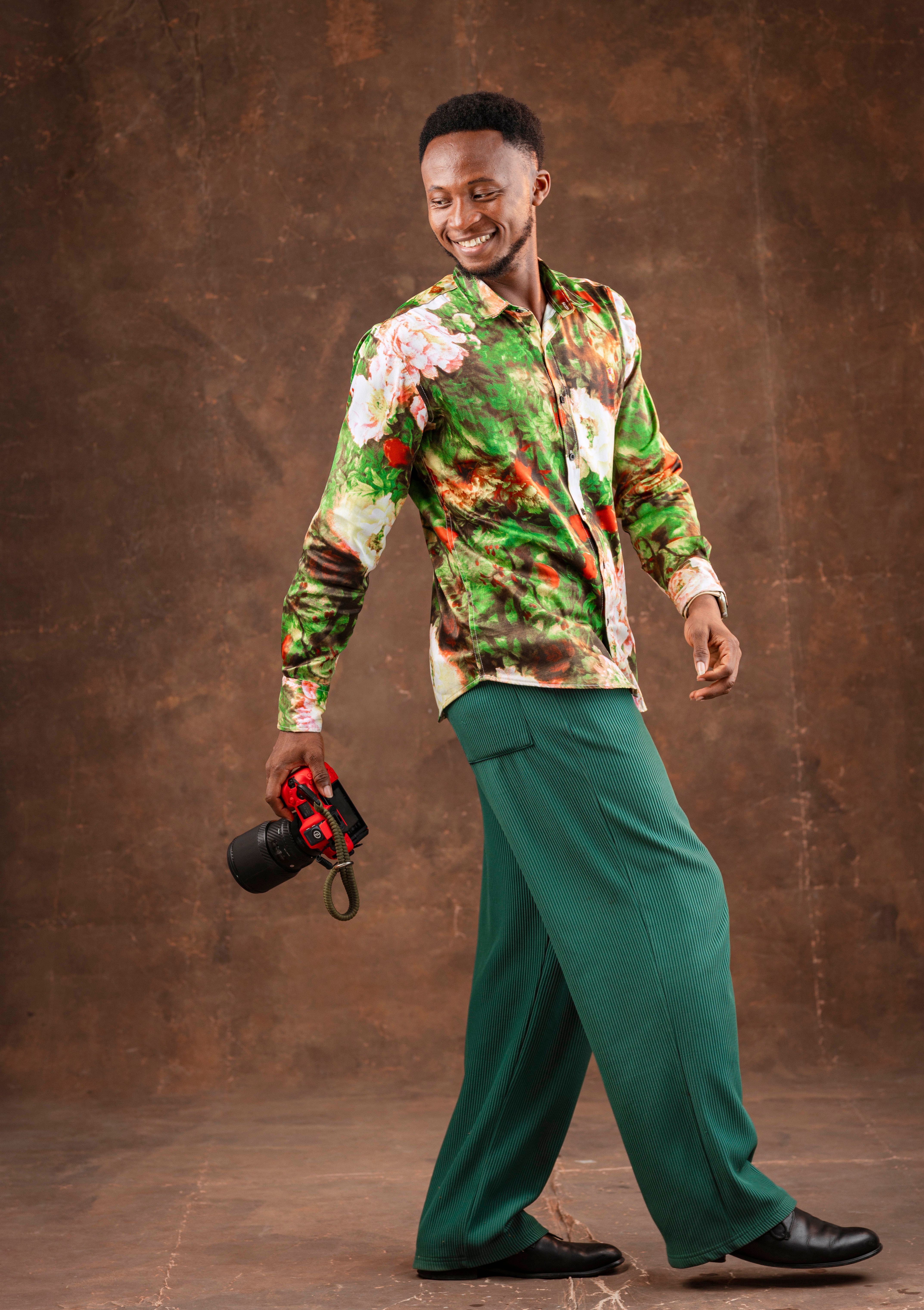Man with camera posing in studio with colorful attire.