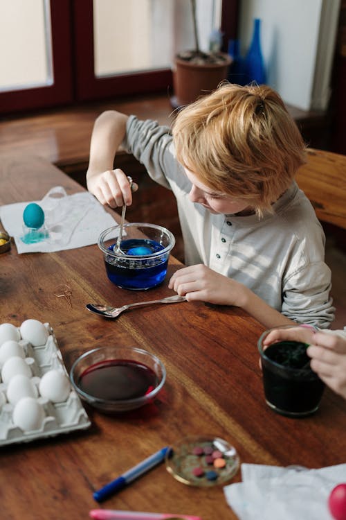 Boy Dipping Egg in Blue Water