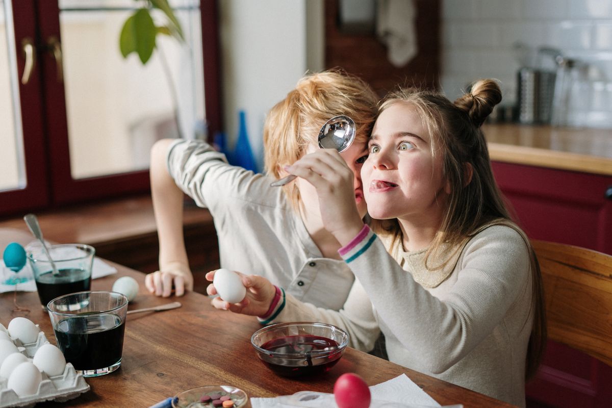 Kids making funny faces while painting eggs