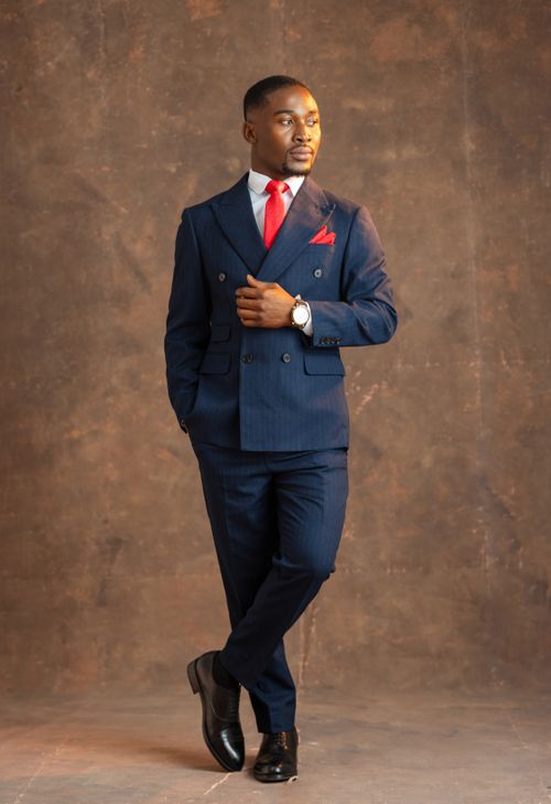 Free Elegant portrait of a man in navy suit with red tie posing indoors. Stock Photo