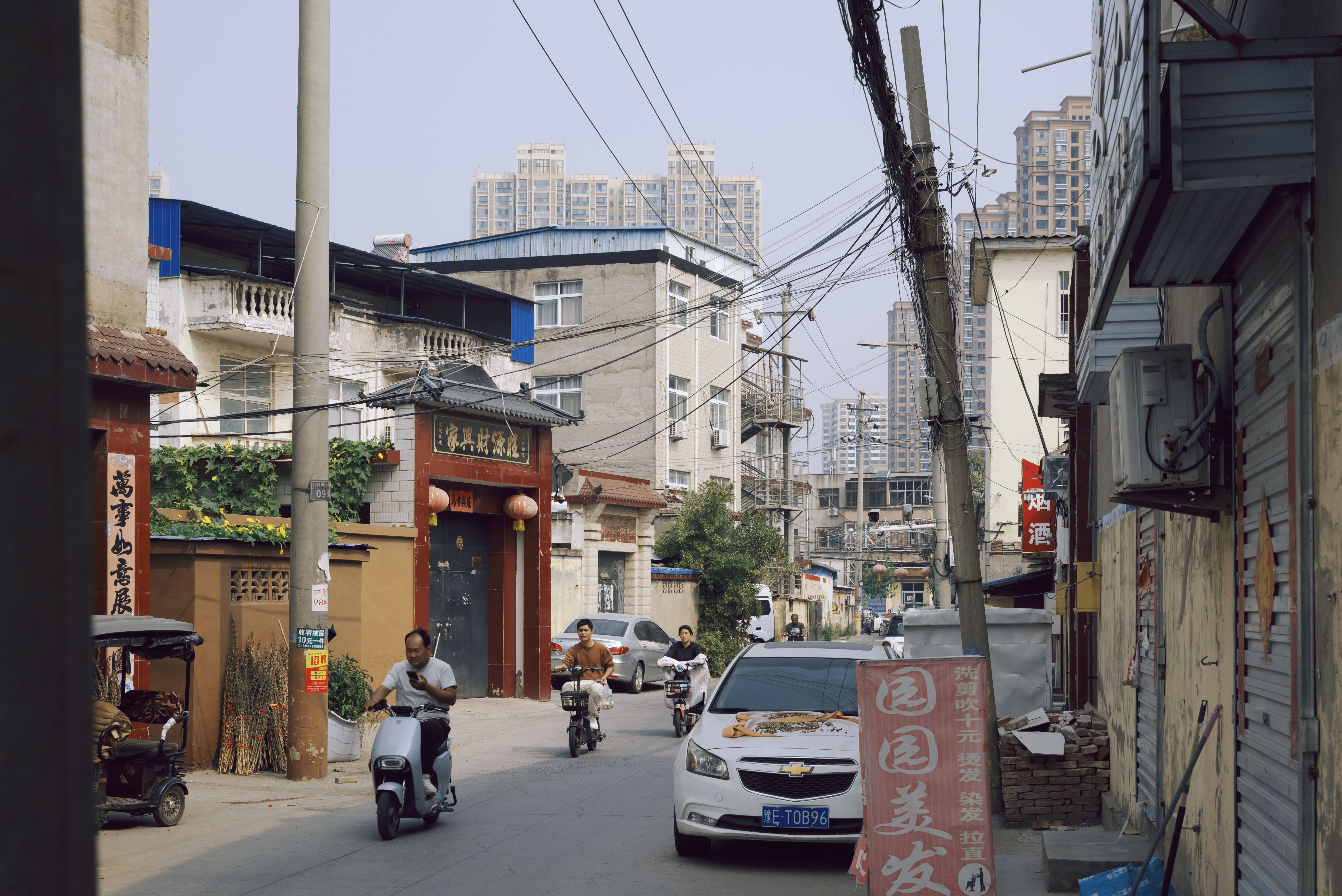 City street with scooters and cars amid urban architecture