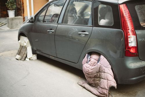 Free A grey car without wheels parked, resting on blocks, outdoors on a city street. Stock Photo