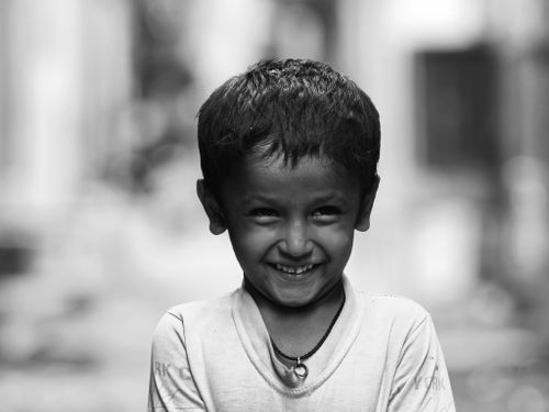 Free A close-up black and white portrait of a joyful child smiling warmly in an outdoor setting. Stock Photo