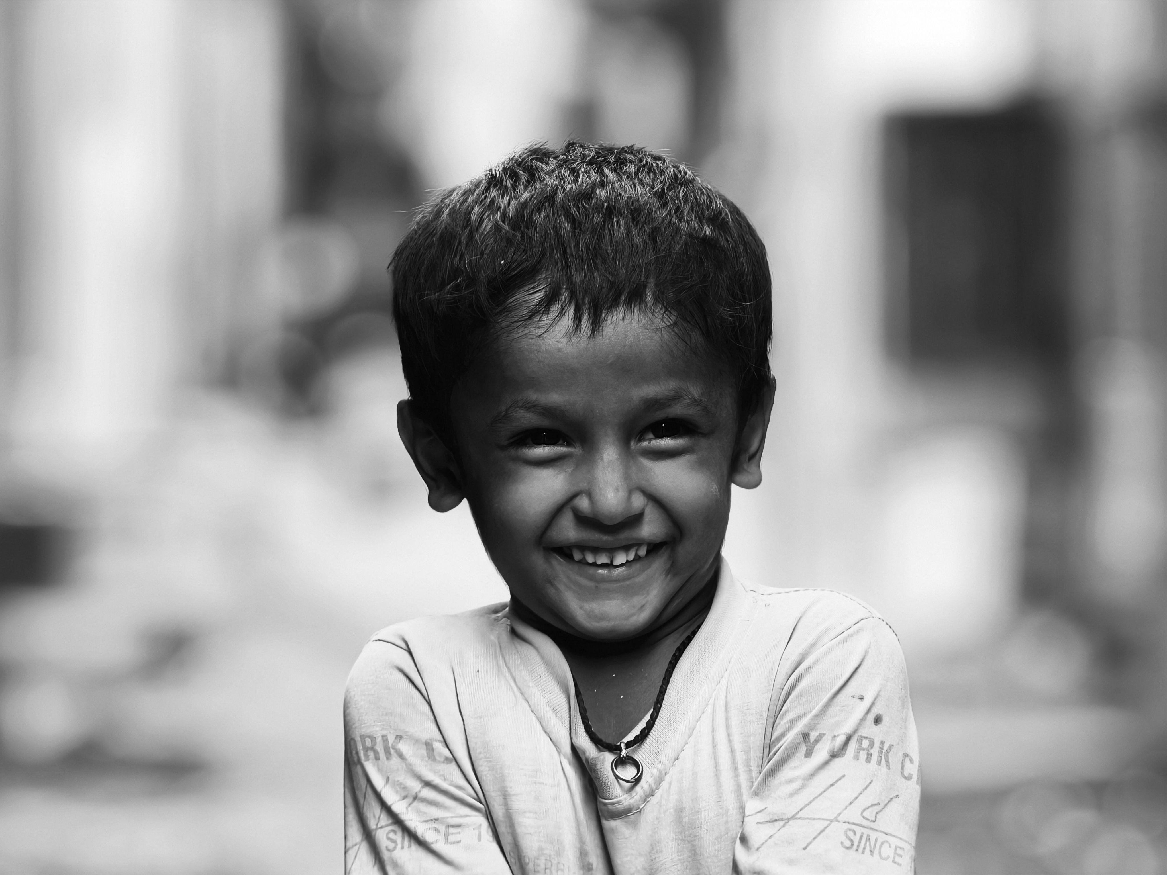 Monochrome portrait of a smiling young child outdoors in a candid moment.
