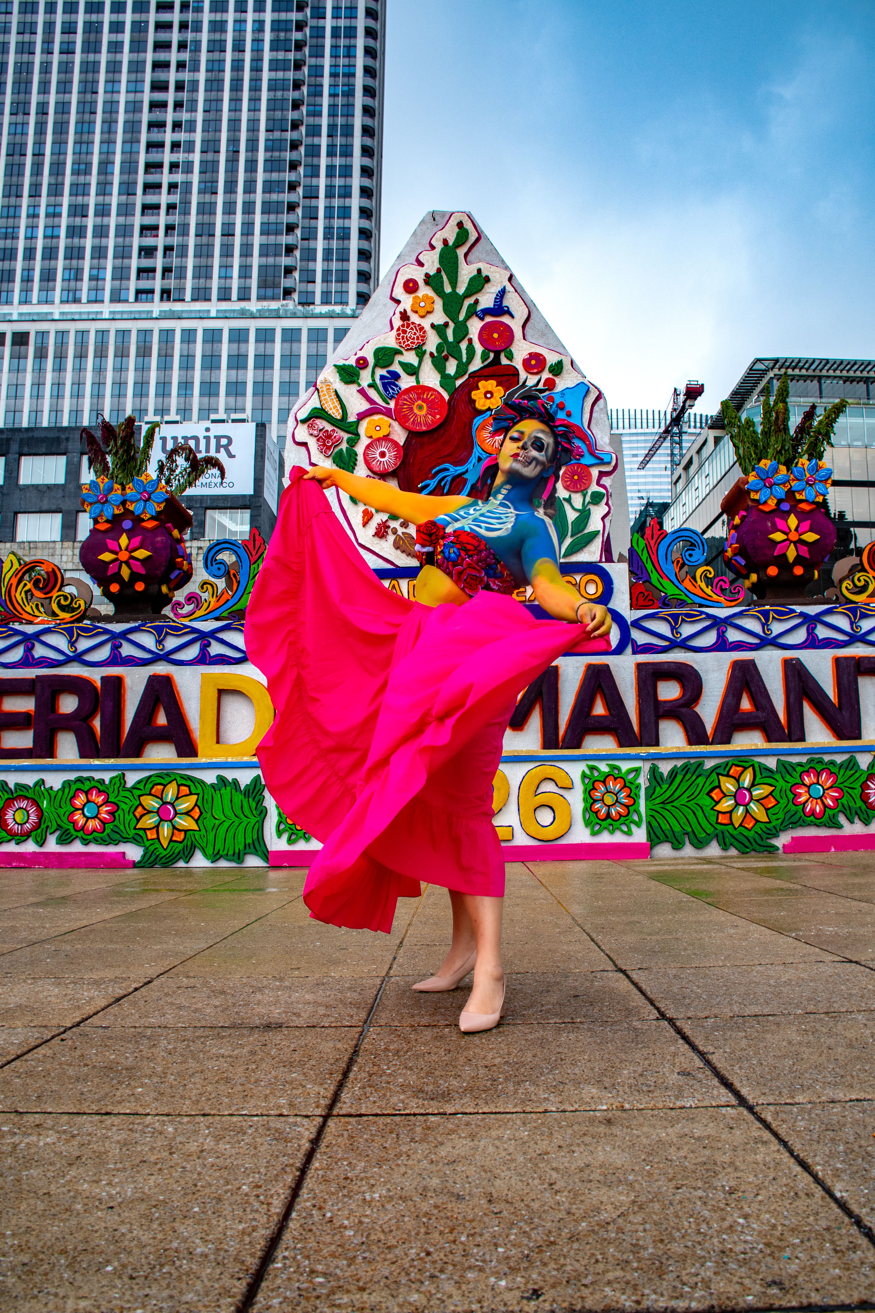Colorful cultural dance in front of artistic backdrop in a city setting.
