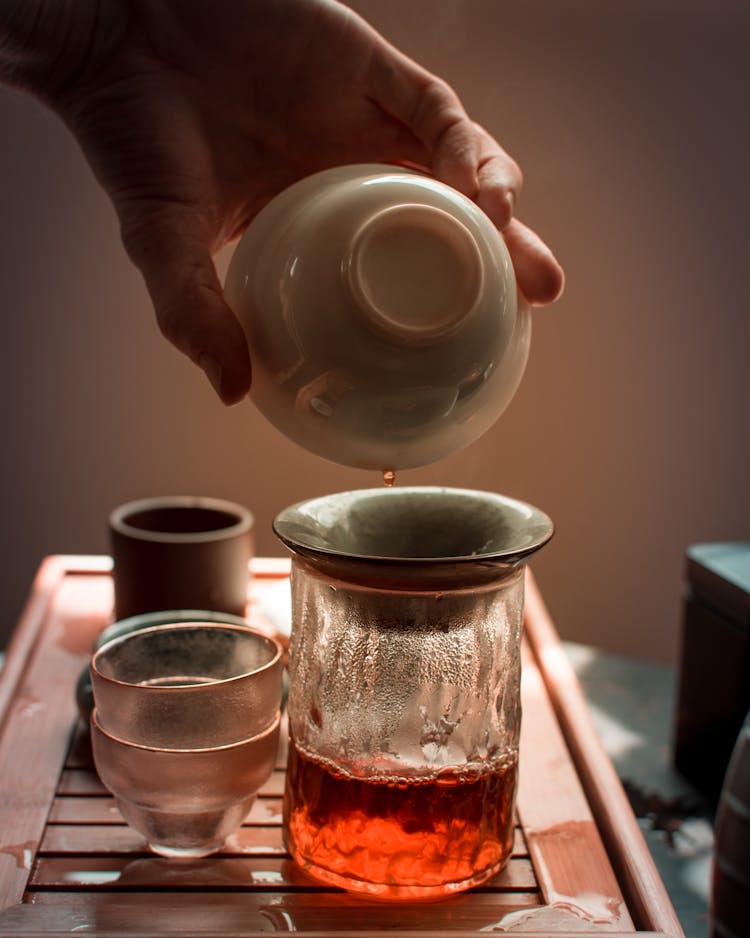 Person Pouring Tea On Clear Drinking Glass