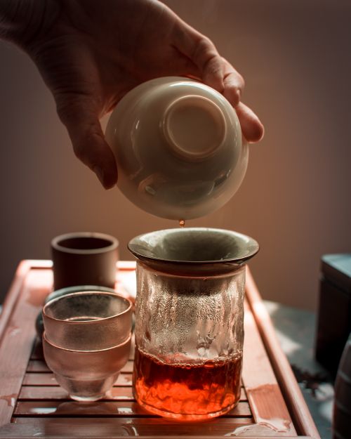 Free Aesthetic setup of tea being poured into a ceramic cup, showcasing warm and moody tones. Stock Photo