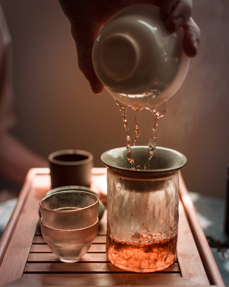 Person Pouring Water On Clear Drinking Glass