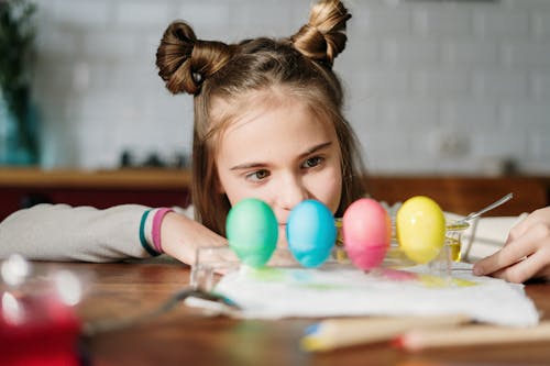 Girl in White and Blue Stripe Long Sleeve Shirt Playing With Orange Balloons