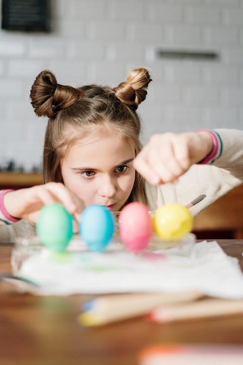 Girl with Cute Hair Buns Making Colorful Easter Eggs