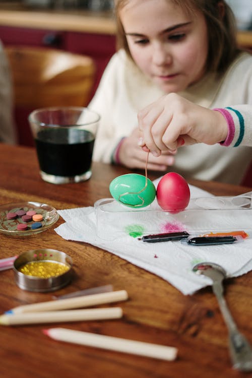 Girl in White Long Sleeve Sweater Holding Colored  Egg