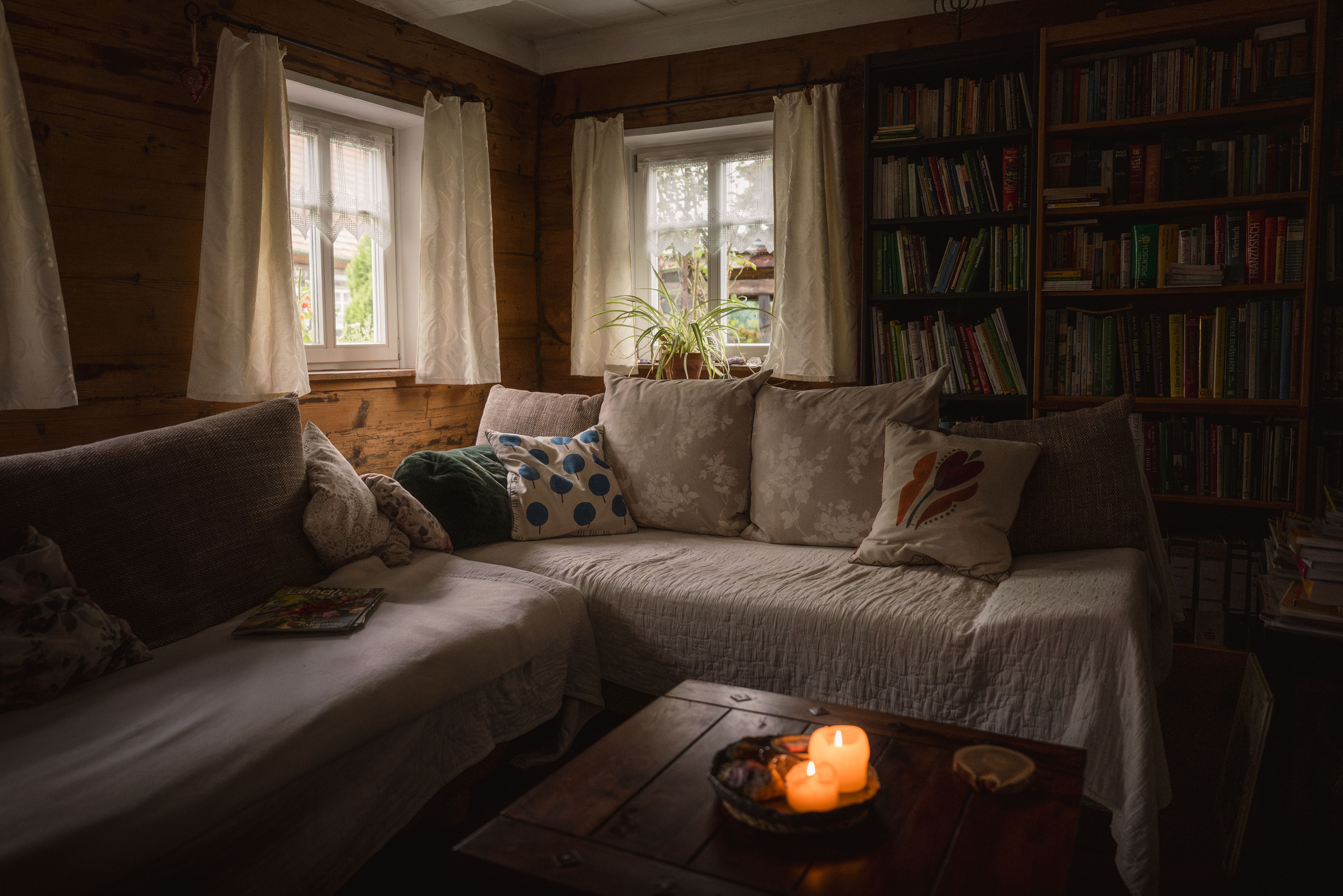 Gemütliches Wohnzimmer mit Ecksofa, Bücherregalen und warmem Kerzenlicht in einer Holzhütte
