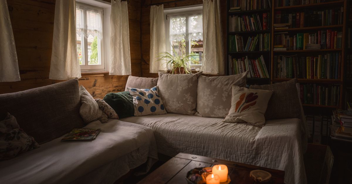 Gemütliches Wohnzimmer mit Ecksofa, Bücherregalen und warmem Kerzenlicht in einer Holzhütte