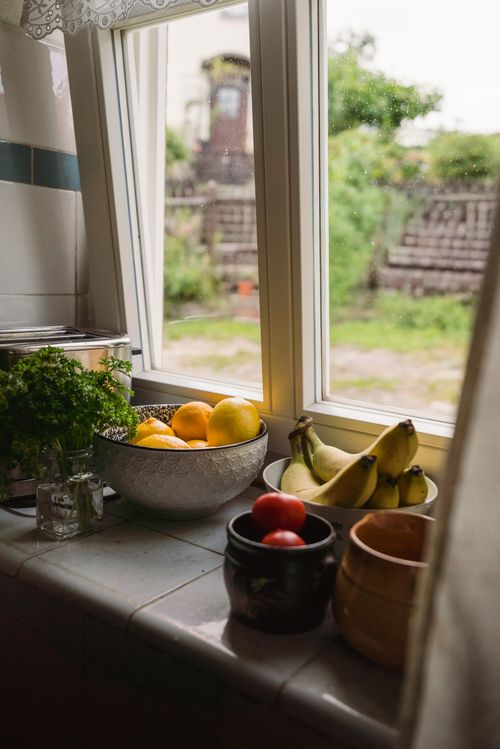 Free Inviting kitchen scene with fresh produce by a garden-facing window in Zittau, Germany. Stock Photo