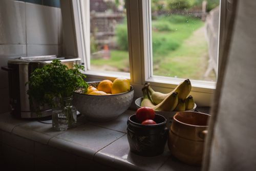 Free A cozy kitchen view with fresh fruit and parsley on a counter. Stock Photo