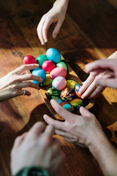 Hands reaching for colorful Easter eggs on a wooden table, celebrating Easter.