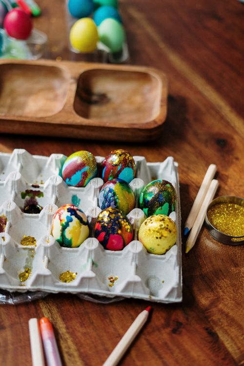 Free Vibrantly painted Easter eggs with glitter on a wooden table, showcasing arts and crafts creativity. Stock Photo