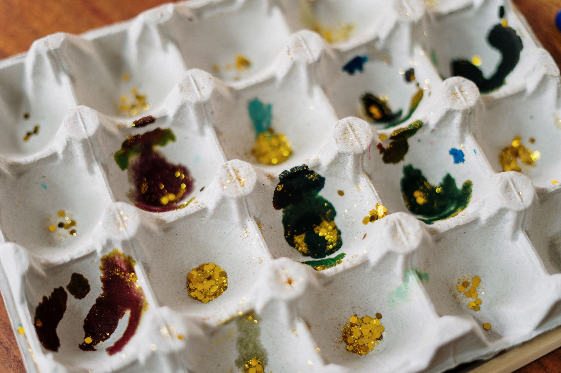 Creative egg carton with colorful paints and glitter, ideal for Easter decoration and crafting.