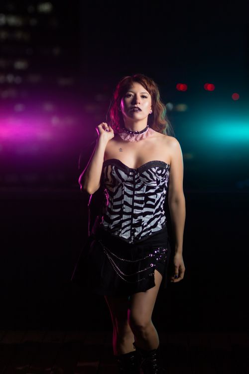Free Gothic fashion model poses in zebra-print corset at night with neon lights. Stock Photo