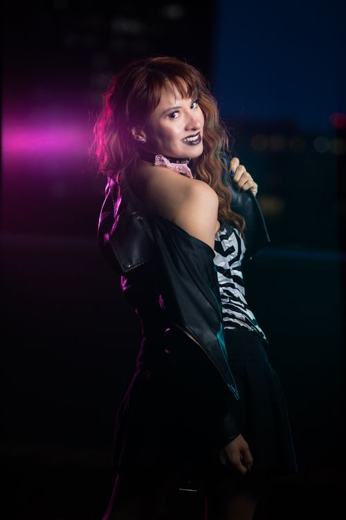 Free Dramatic portrait of a woman with red hair in gothic attire under city lights. Stock Photo