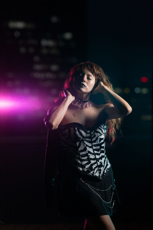 Free Striking portrait of a woman in gothic fashion with city lights backdrop. Stock Photo