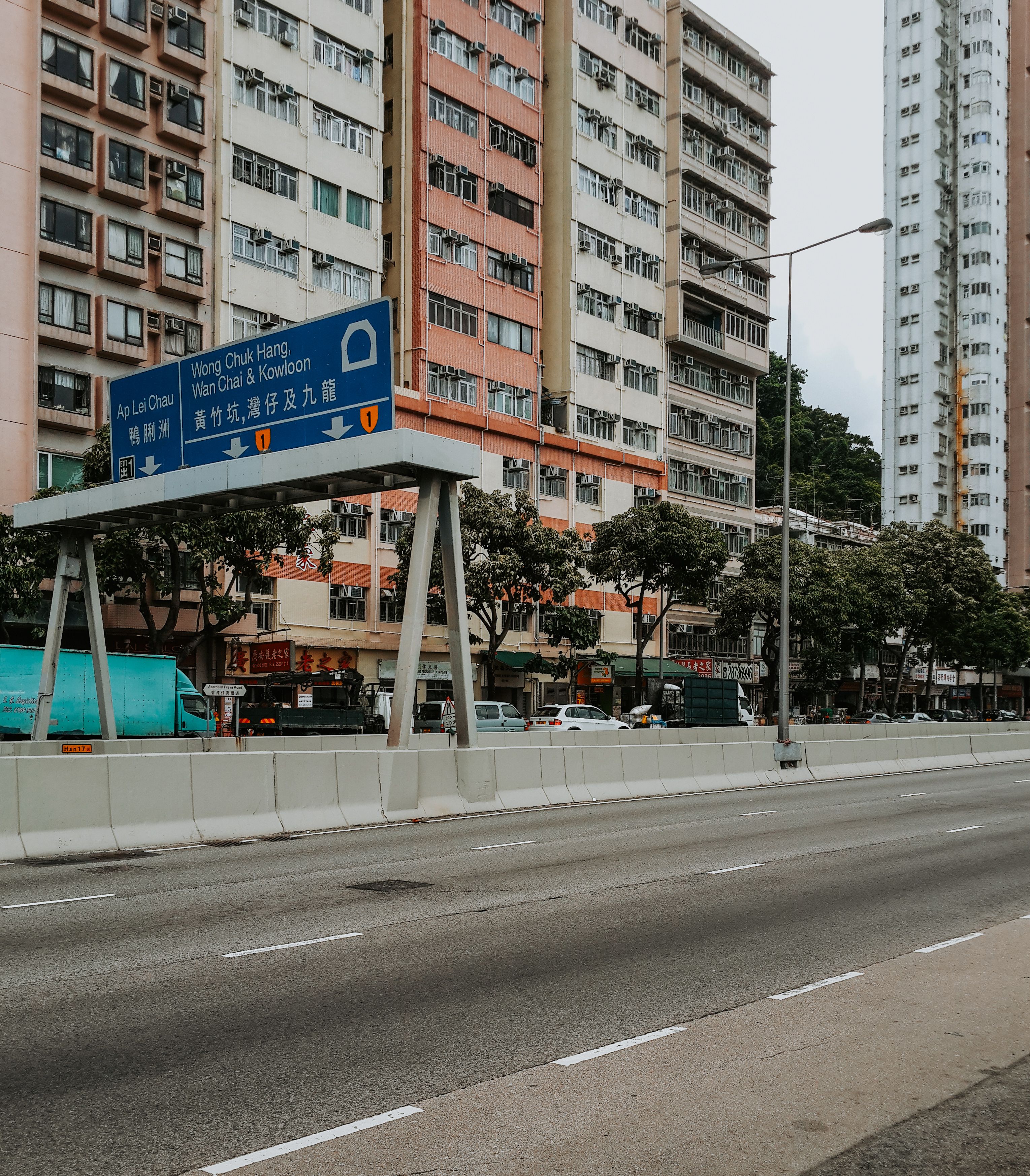 A bustling cityscape in Hong Kong featuring high-rise buildings and a prominent road sign. Ideal for travel and architecture themes.
