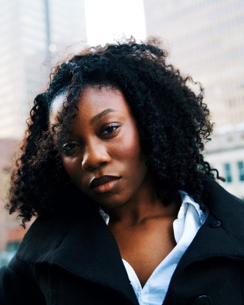 Free Close-up portrait of a woman with curly hair against an urban backdrop. Stock Photo